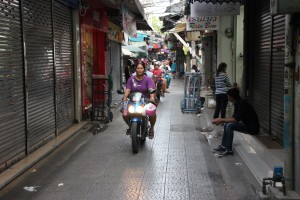 Rollerfahrer in einer Seitenstraße in China Town Bangkok